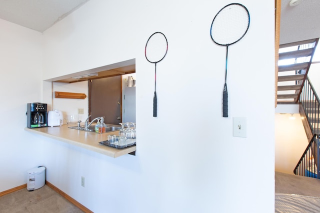 kitchen featuring light countertops, carpet flooring, a sink, and baseboards