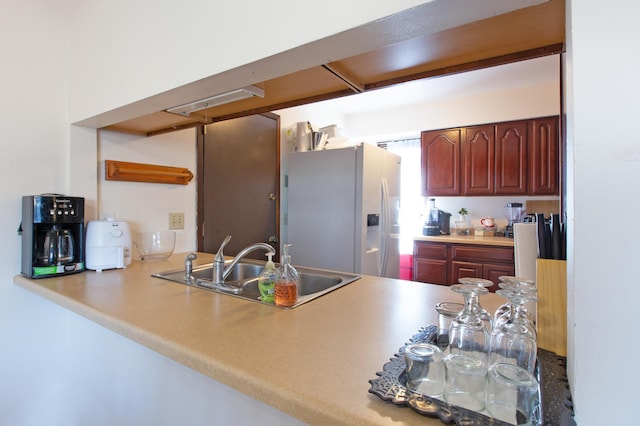 kitchen with a peninsula, stainless steel fridge, and a sink