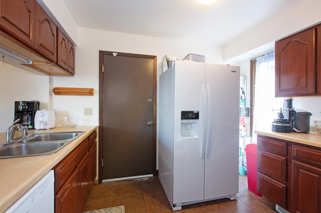 kitchen with white appliances, light countertops, a sink, and dark tile patterned floors