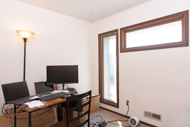 office space with visible vents, light carpet, and baseboards