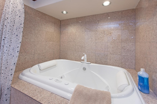 full bath with a jetted tub, tile walls, and recessed lighting