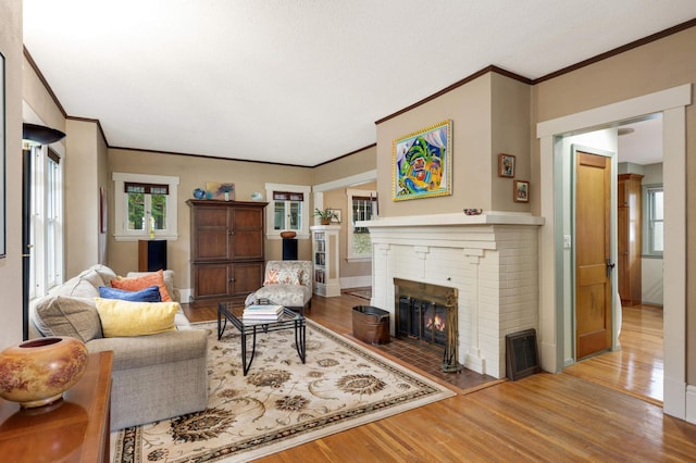 living room with ornamental molding, a fireplace, baseboards, and wood finished floors