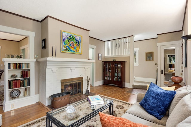 living room featuring ornamental molding, a brick fireplace, baseboards, and wood finished floors