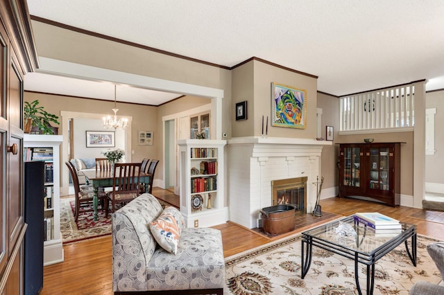 living area featuring ornamental molding, a brick fireplace, an inviting chandelier, and wood finished floors