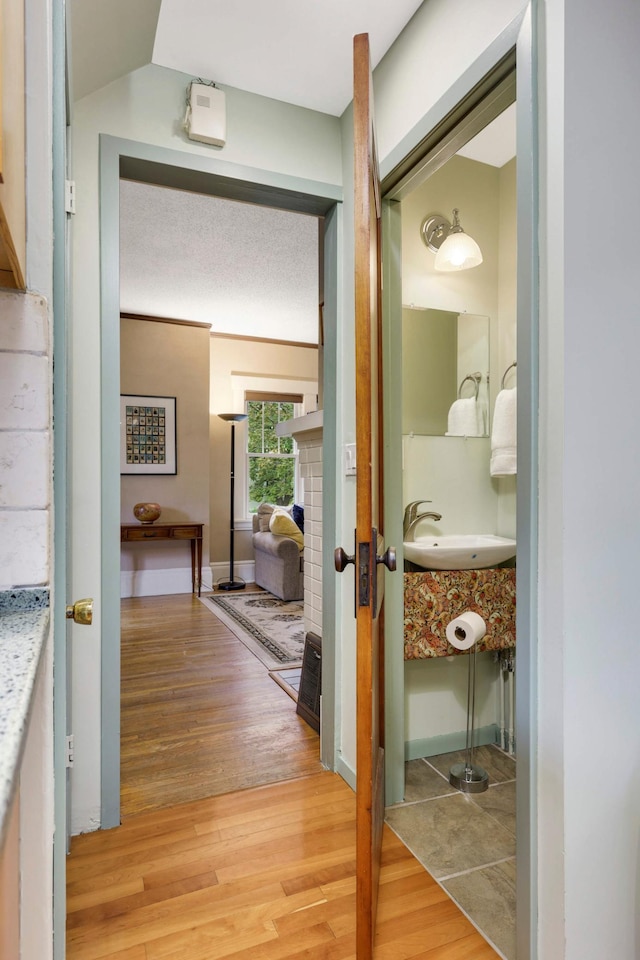 hallway featuring light wood finished floors, a sink, and baseboards