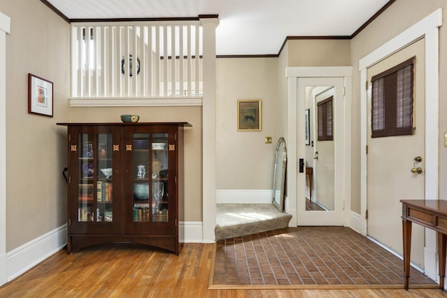 entryway with baseboards, crown molding, and wood finished floors