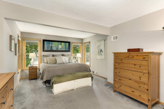 bedroom featuring baseboards, a textured ceiling, visible vents, and light colored carpet