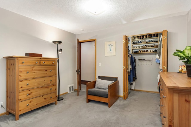 living area featuring a textured ceiling, baseboards, visible vents, and light colored carpet