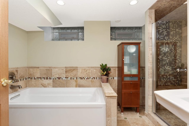 full bathroom featuring a stall shower, recessed lighting, a bath, and tile walls