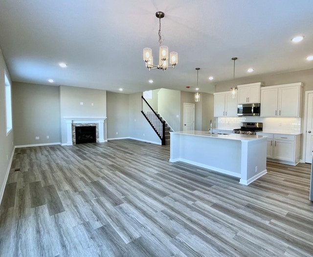 kitchen with a fireplace, stainless steel appliances, recessed lighting, light wood-style floors, and a sink