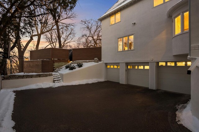 exterior space with a garage, driveway, fence, and stucco siding