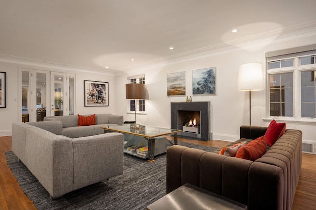 living area with french doors, a fireplace with flush hearth, dark wood finished floors, and crown molding