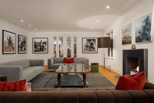 living area featuring a fireplace with flush hearth, french doors, wood finished floors, and crown molding