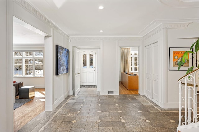 foyer featuring baseboards, granite finish floor, and crown molding