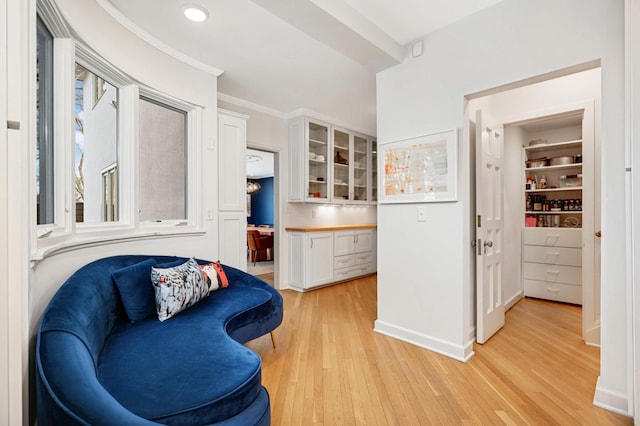 living area featuring light wood-style flooring, baseboards, and crown molding