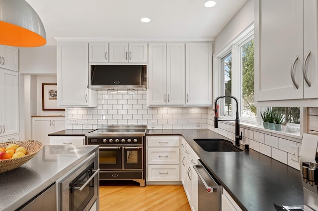 kitchen with stainless steel dishwasher, double oven range, white cabinetry, and a sink