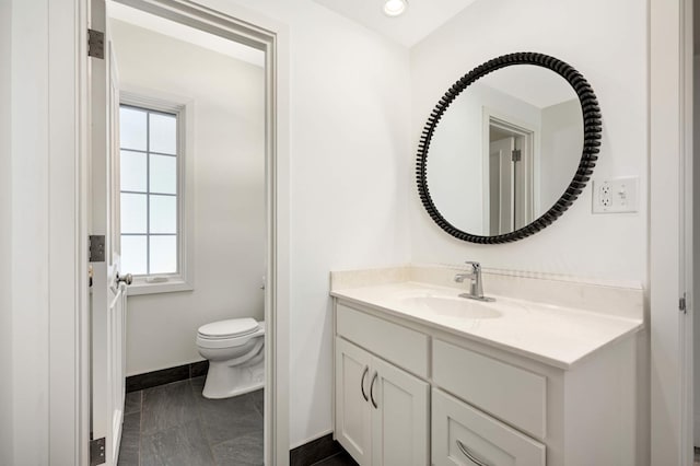 bathroom with baseboards, vanity, and toilet