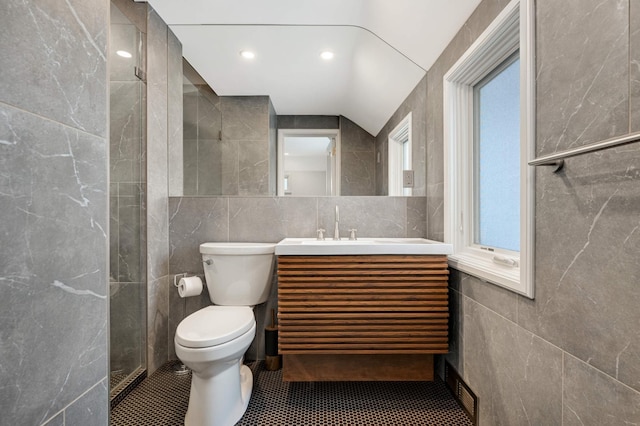 bathroom with toilet, vanity, tile walls, and tile patterned floors