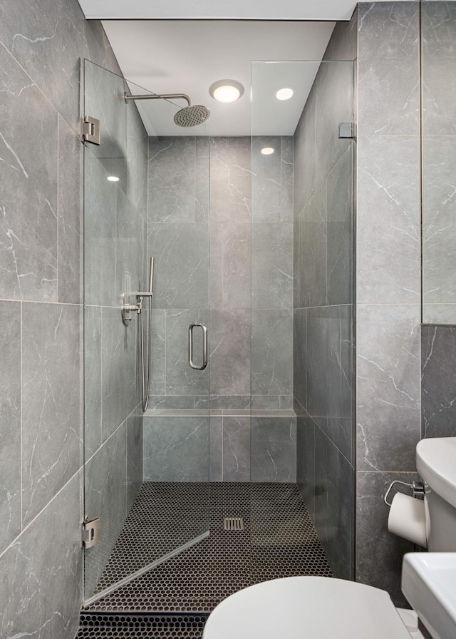 bathroom featuring toilet, a stall shower, and tile walls