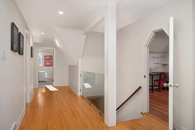 hallway with baseboards, recessed lighting, an upstairs landing, and light wood-style floors