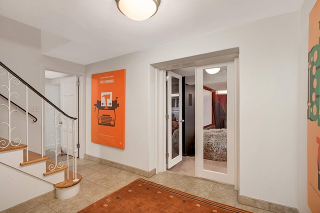 interior space featuring light tile patterned floors, baseboards, and stairs