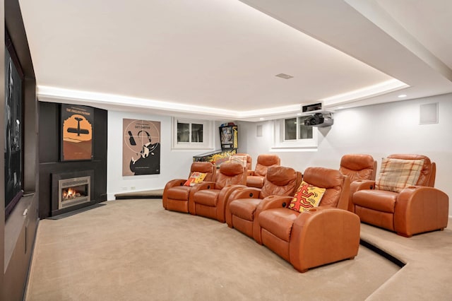 carpeted home theater with recessed lighting, a raised ceiling, and a fireplace