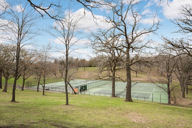 exterior space featuring a tennis court, fence, and a lawn