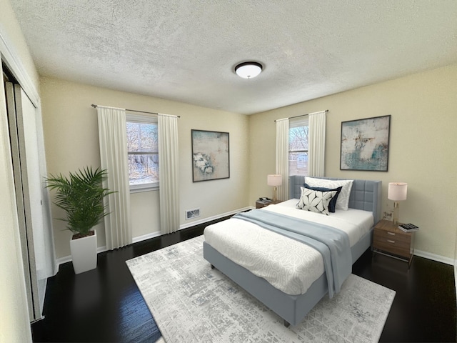 bedroom featuring a closet, a textured ceiling, baseboards, and wood finished floors