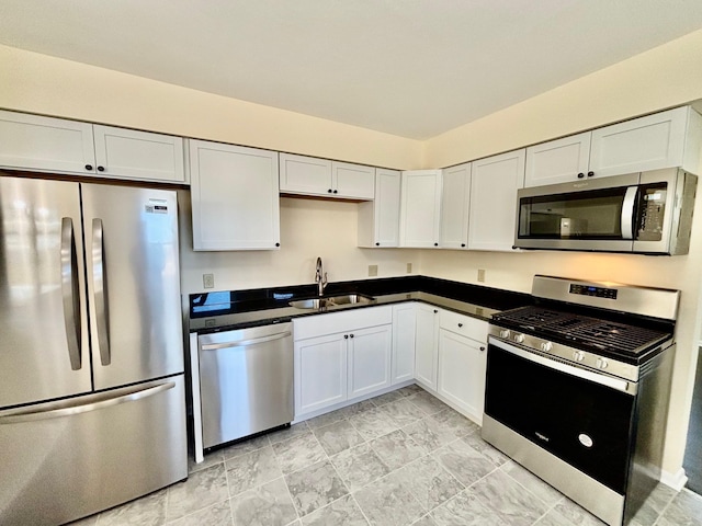 kitchen featuring dark countertops, white cabinetry, appliances with stainless steel finishes, and a sink