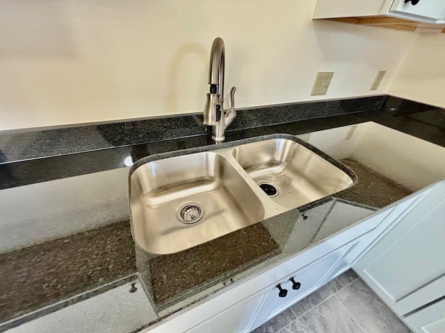 room details featuring dark stone counters and a sink