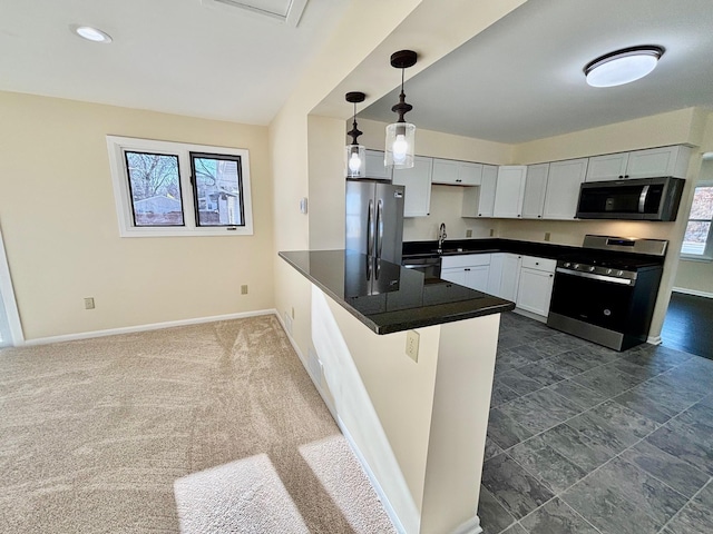 kitchen with a peninsula, baseboards, appliances with stainless steel finishes, dark countertops, and pendant lighting