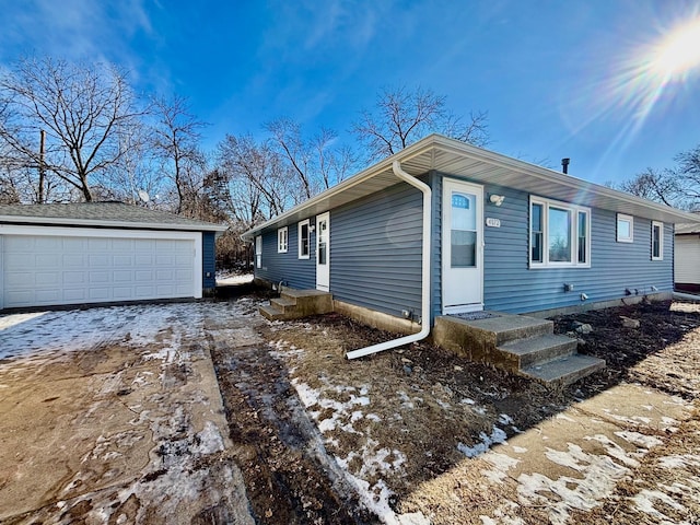 view of side of property with entry steps, a detached garage, and an outbuilding