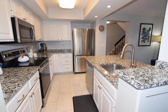 kitchen with appliances with stainless steel finishes, light stone countertops, white cabinetry, a sink, and recessed lighting