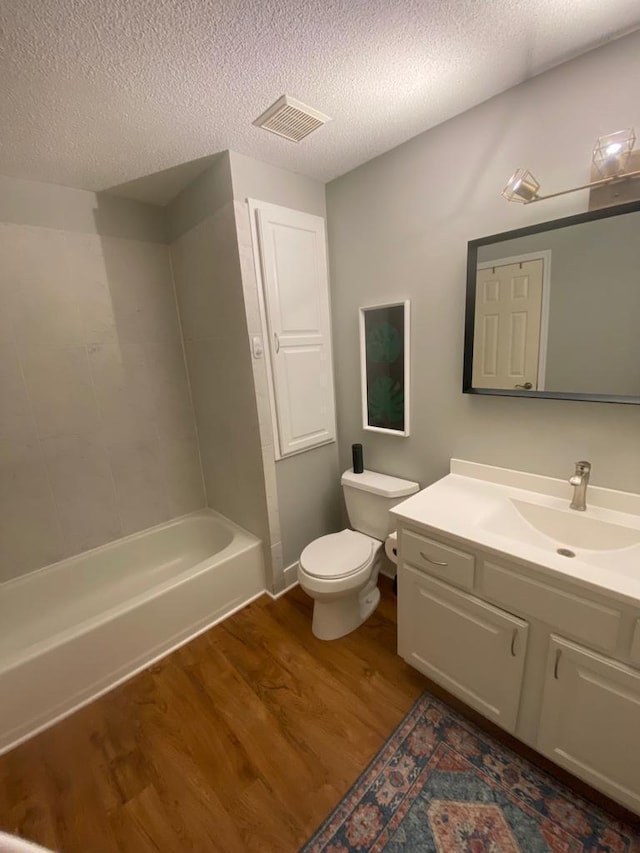 bathroom featuring visible vents, toilet, vanity, a textured ceiling, and wood finished floors