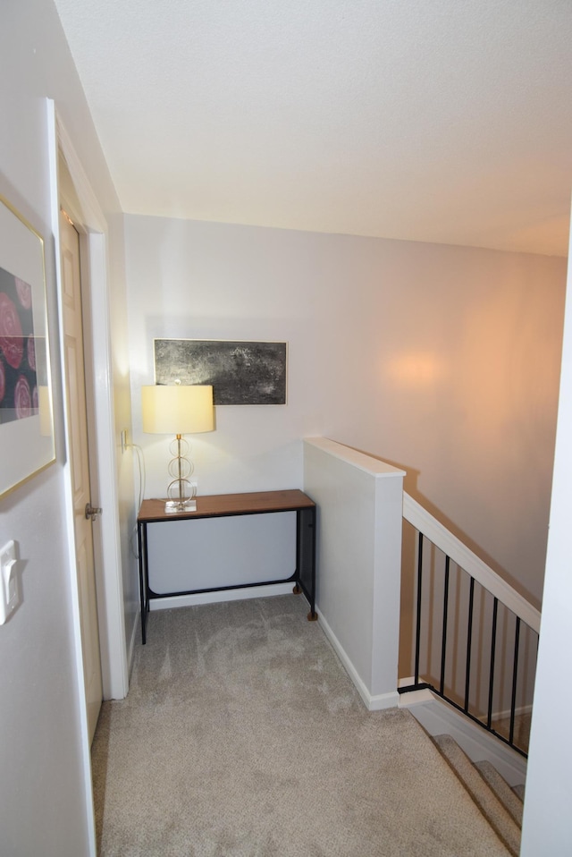 hall with baseboards, carpet flooring, and an upstairs landing