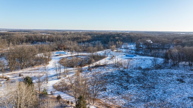 snowy aerial view featuring a wooded view