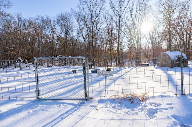 snowy yard featuring a gate and fence