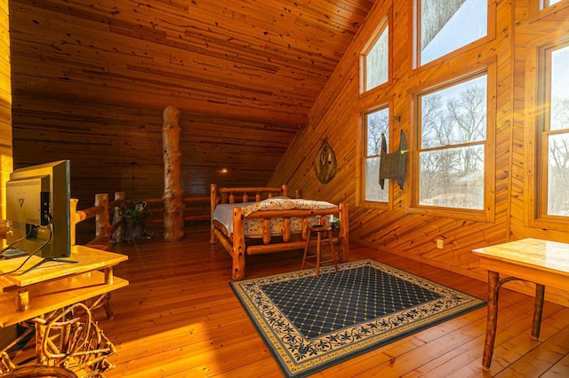 bedroom with high vaulted ceiling, wood ceiling, wooden walls, and hardwood / wood-style flooring