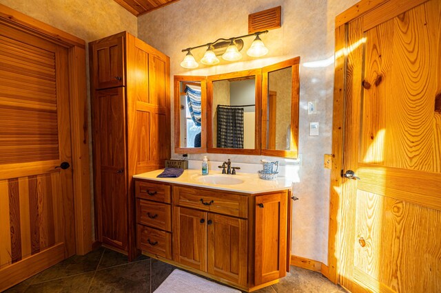 bathroom featuring curtained shower, visible vents, vanity, baseboards, and tile patterned floors