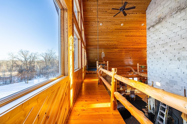 hall featuring hardwood / wood-style floors, brick wall, wooden walls, and an upstairs landing