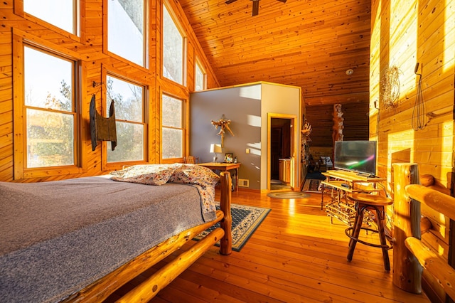 bedroom with wood-type flooring, wood walls, high vaulted ceiling, and multiple windows