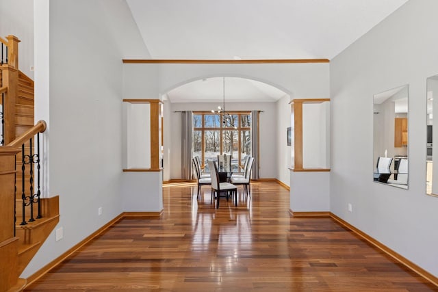 dining space featuring wood finished floors, baseboards, arched walkways, and a chandelier