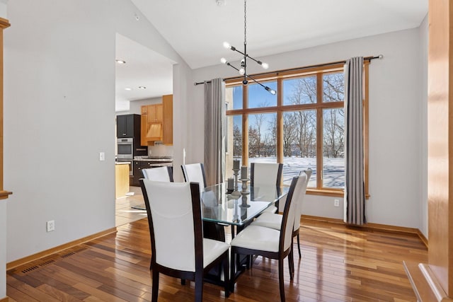 dining area with a chandelier, baseboards, light wood-style floors, and vaulted ceiling