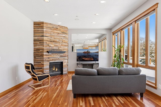 living room featuring recessed lighting, baseboards, a large fireplace, and wood finished floors