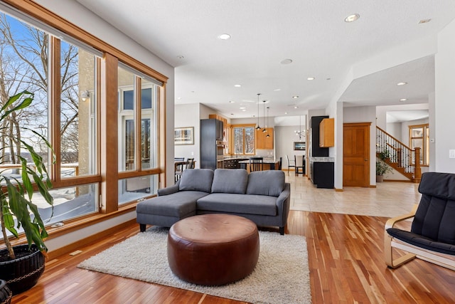 living room featuring stairway, light wood-style flooring, and a wealth of natural light