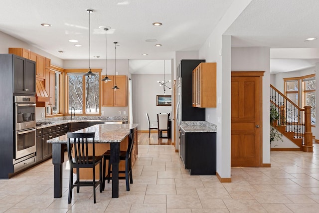 kitchen with a breakfast bar area, light stone counters, baseboards, stainless steel appliances, and a center island