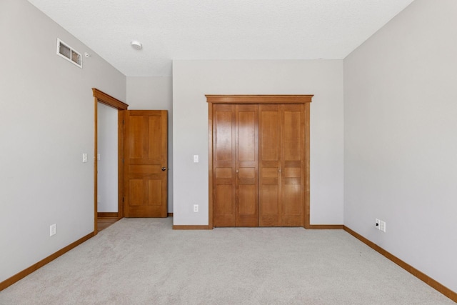 unfurnished bedroom with baseboards, visible vents, a closet, and light carpet