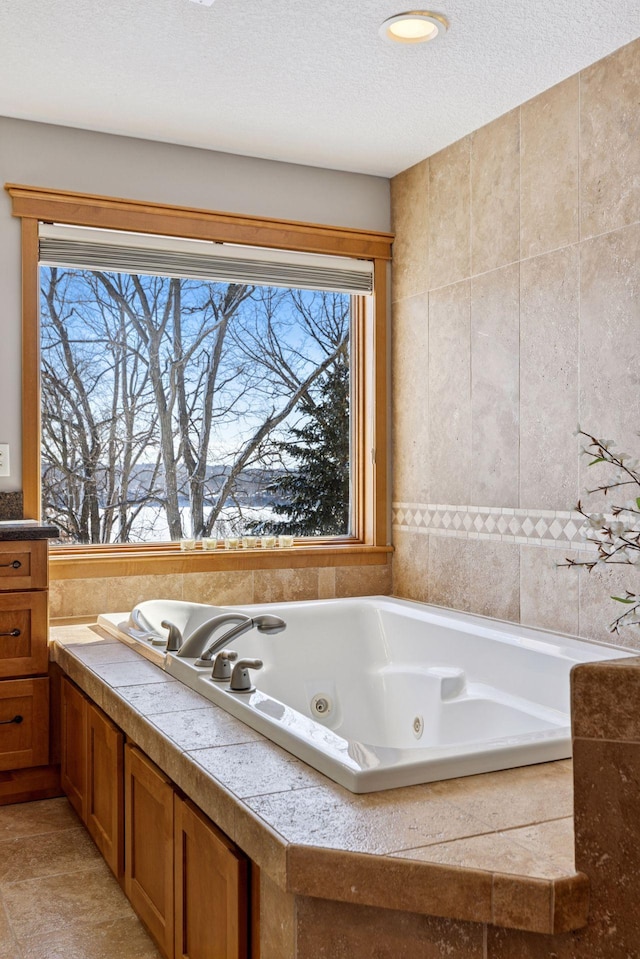 full bathroom featuring a jetted tub and a textured ceiling