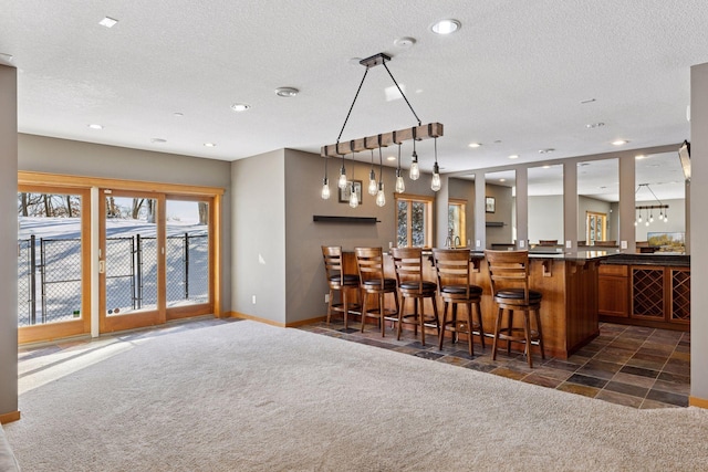 bar featuring pendant lighting, a textured ceiling, recessed lighting, dark colored carpet, and bar area