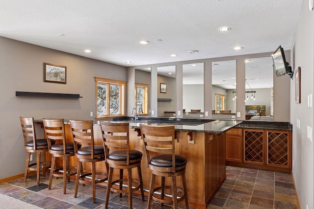 bar featuring stone finish floor, recessed lighting, a textured ceiling, and baseboards